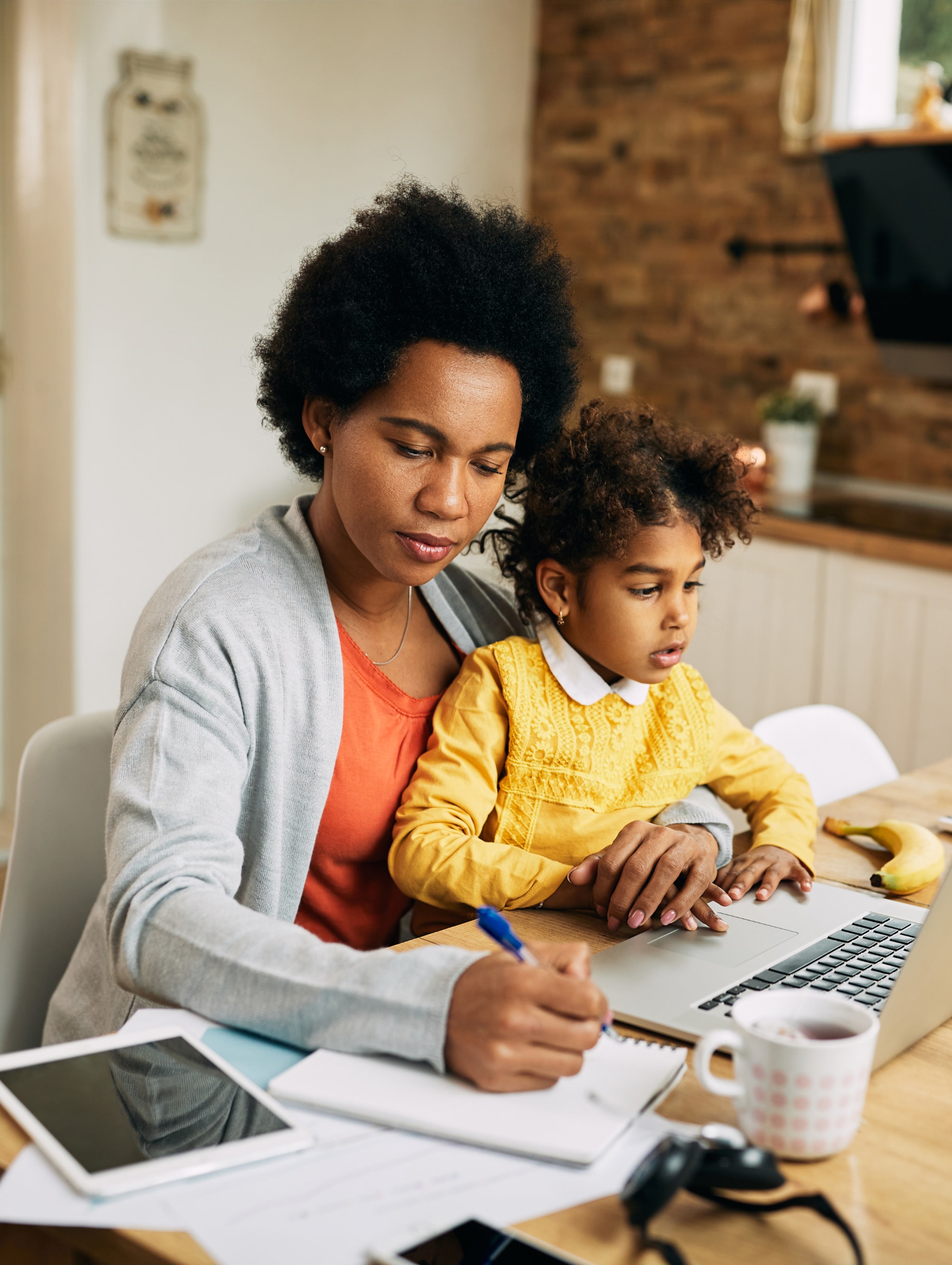 Woman doing work on a laptop with child in her lap