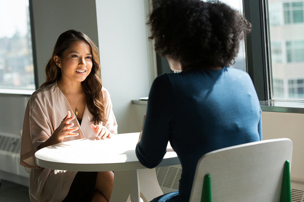 Two women talking at a table at work