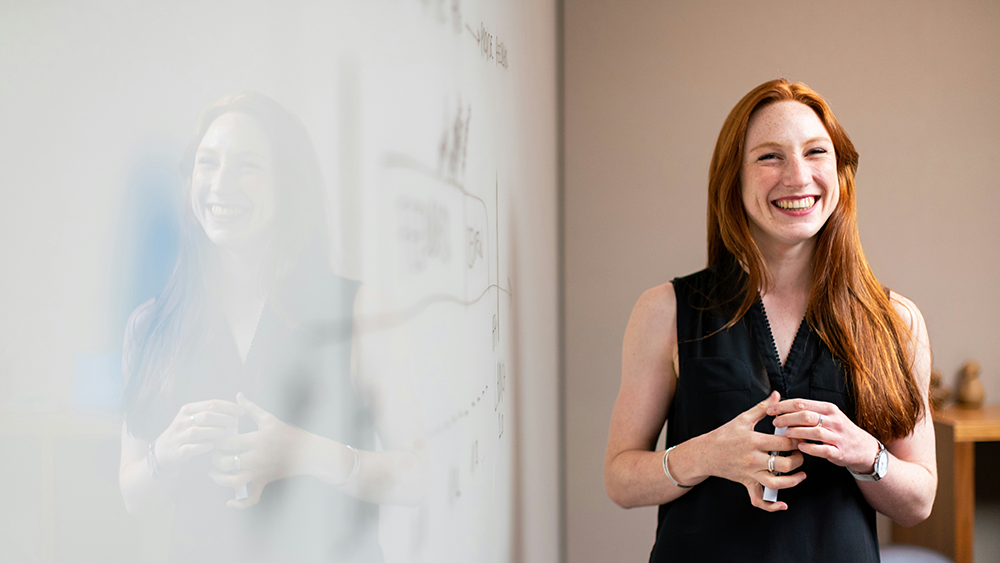 Woman smiling in front of whiteboard